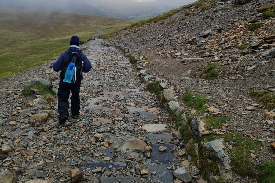 A hiker walking along one of Snowdon’s trails in Snowdonia National Park, Wales, surrounded by rugged mountain scenery.