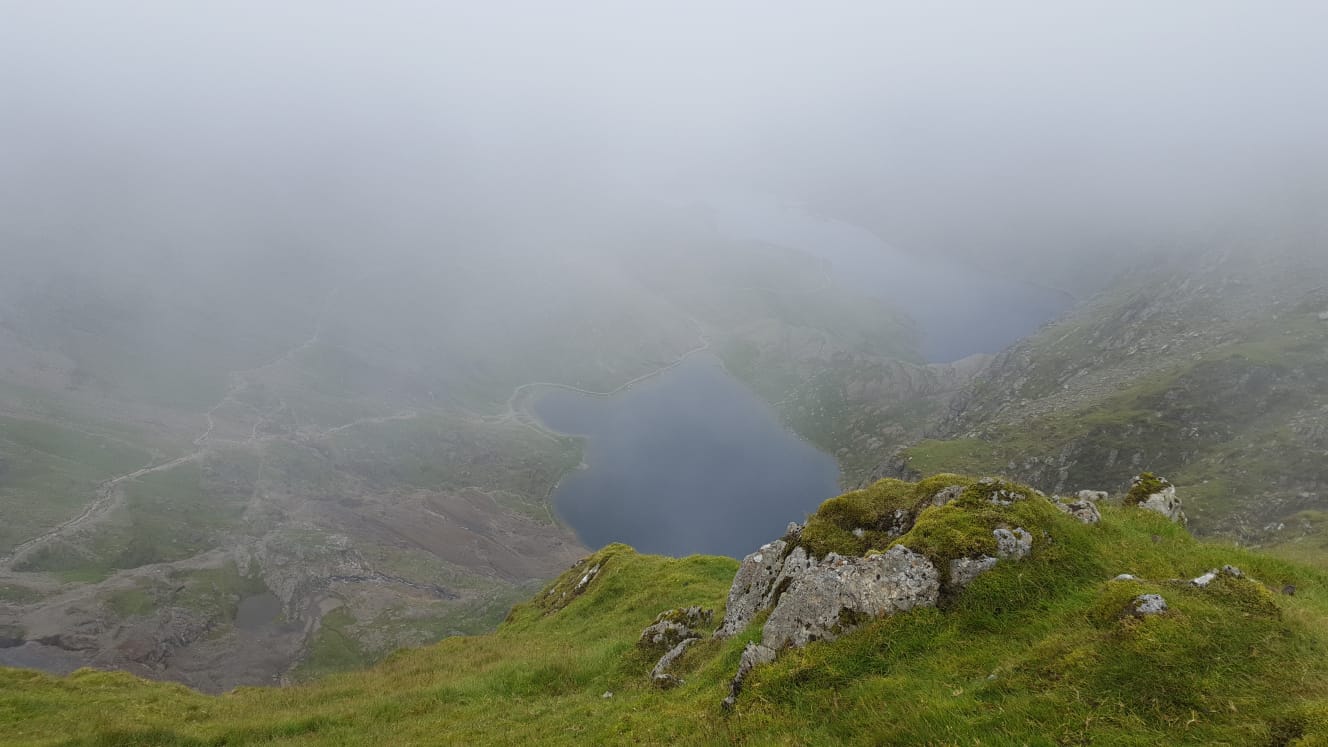 Snowdon’s rugged mountain landscape in Snowdonia National Park, Wales, showing rocky trails and dramatic weather conditions, with no people present.